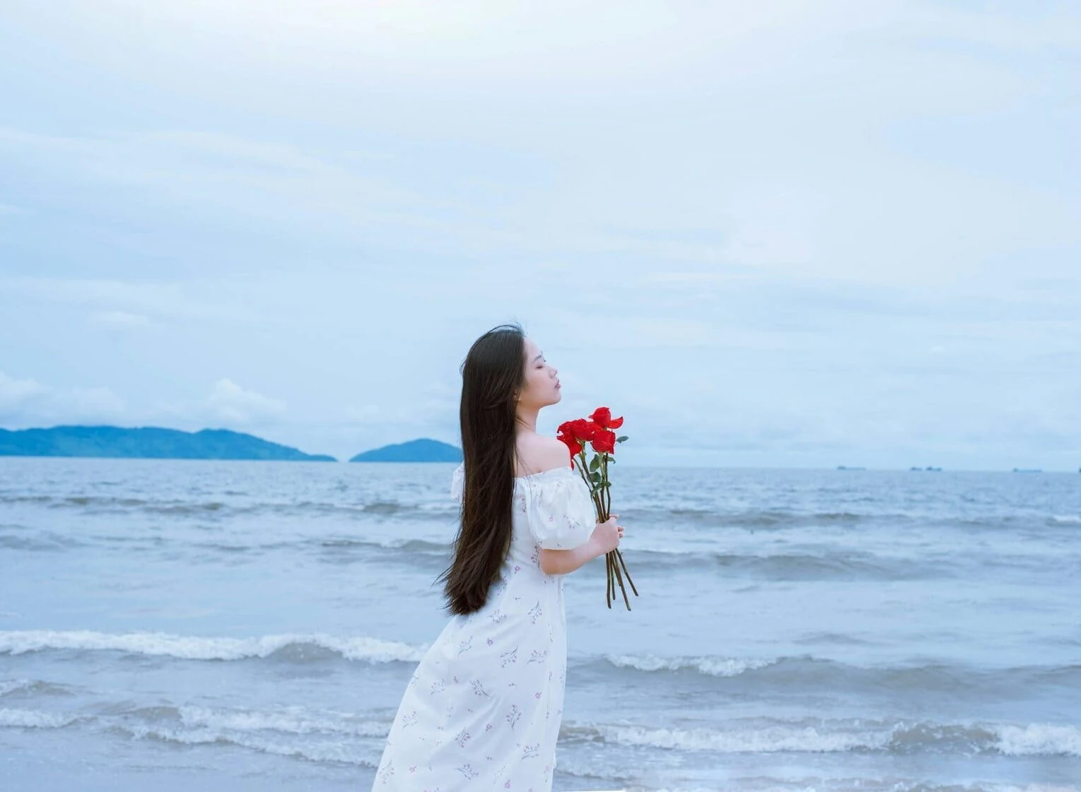 Woman holding red roses by the sea in Tetouan, Morocco